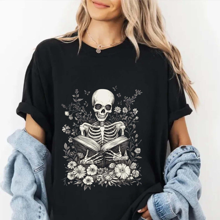 Gothic shirt featuring skeleton reading a book surrounded by flowers on a woman in a casual outfit.